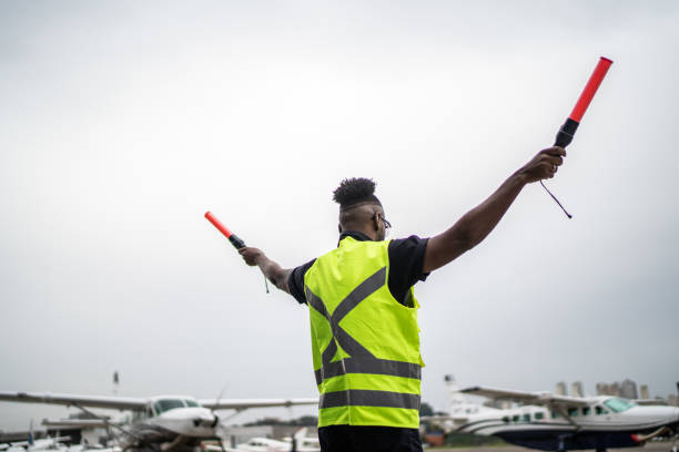 istock Man signaling the pilot with marshalling wands on airport 1487574157