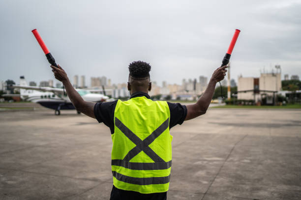 istock Man signaling the pilot with marshalling wands on airport 1487574161