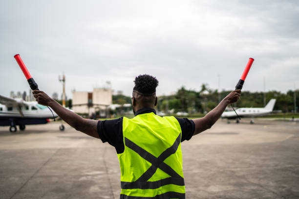 istock Man signaling the pilot with marshalling wands on airport 1487574178