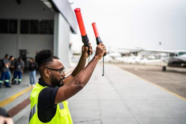 istock Man signaling the pilot with marshalling wands on airport 1487574207