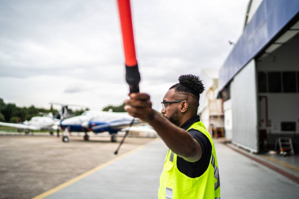 istock Man signaling the pilot with marshalling wands on airport 1487574211