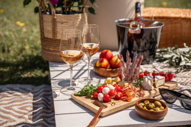 copas de vino rosado con aperitivos de comida de picnic antipasti en la mesa de fiesta del jardín soleado - cheese wine food appetizer fotografías e imágenes de stock