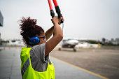 Woman signaling the pilot with marshalling wands on airport