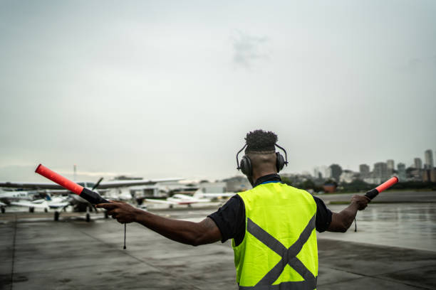 istock Man signaling the pilot with marshalling wands on airport 1487574785