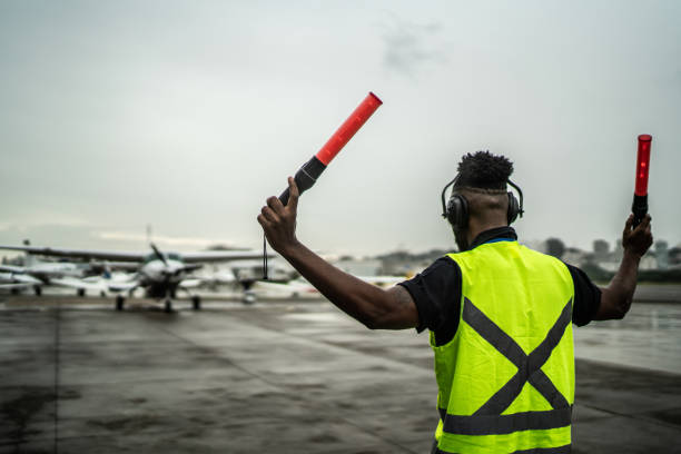 istock Man signaling the pilot with marshalling wands on airport 1487574788