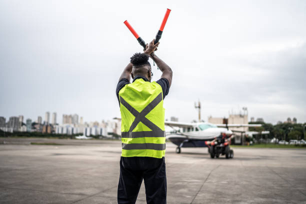istock Man signaling the pilot with marshalling wands on airport 1487574807