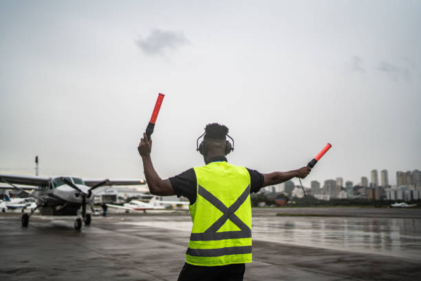 istock Man signaling the pilot with marshalling wands on airport 1487574810