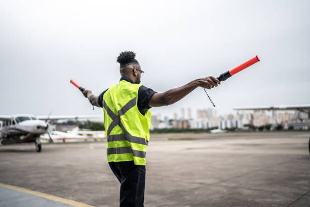 istock Man signaling the pilot with marshalling wands on airport 1487574812