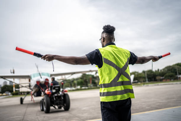 istock Man signaling the pilot with marshalling wands on airport 1487574820