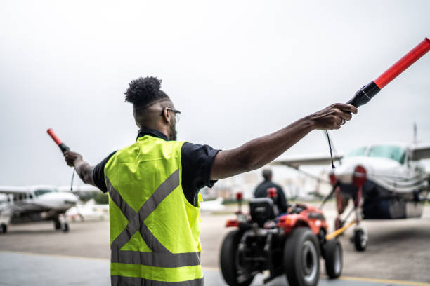 istock Man signaling the pilot with marshalling wands on airport 1487574827