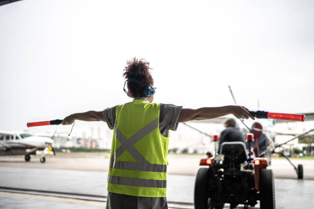 Woman signaling the pilot with marshalling wands on airport