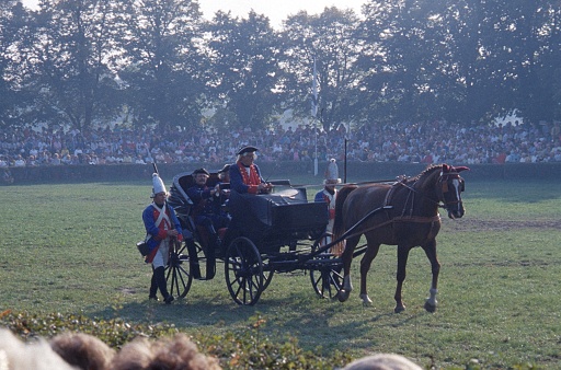 Berlin (West), Germany, 1990. Historical carriage  with  horses and escorted by two grenadiers at an event in Berlin West. Also: participants and spectators.