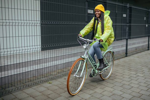 Cheerful woman riding bicycle in raincoat.