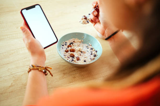 istock Woman uses her mobile phone and has breakfast 1487581865