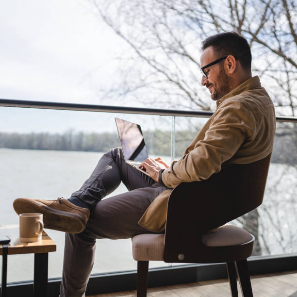 istock Man with cup of coffee Use Laptop Computer on Terrace Balcony 1487582063