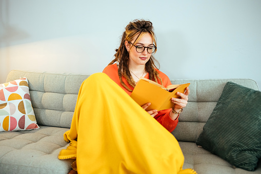 Young woman reading a book at home.