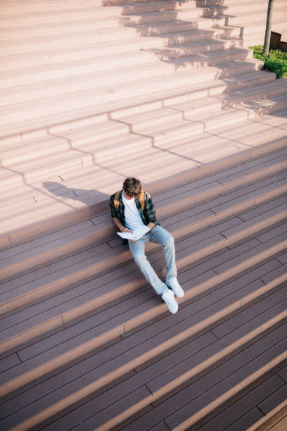 istock College student sitting on steps with a book after class 1487587311