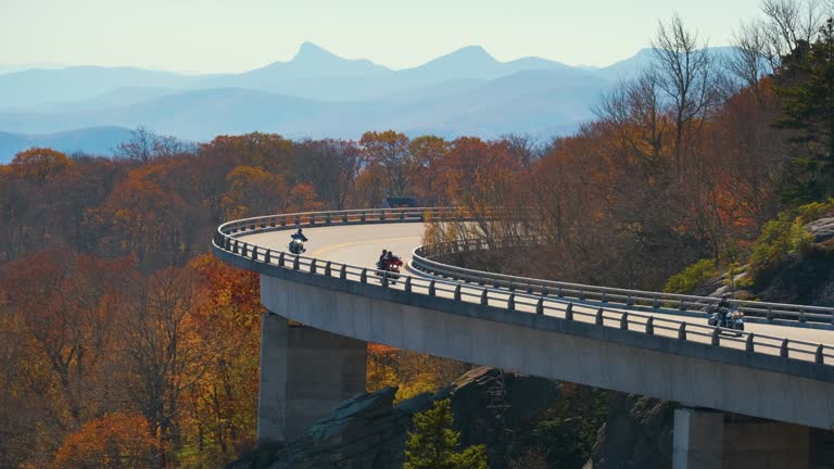 Mountain fall landscape with Linn Cove Viaduct, near Blowing Rock, Blue Ridge Parkway, North Carolina, USA. Driving cars on scenic road between autumnal woods