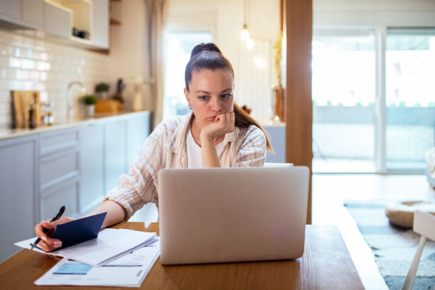istock Young woman going over her finances at home while using her laptop 1487587717