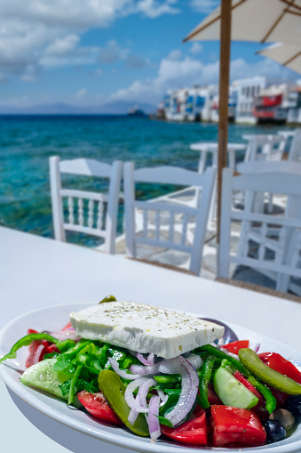 Greek salad lying on the table on the beach in Mykonos, one of the Greek islands.