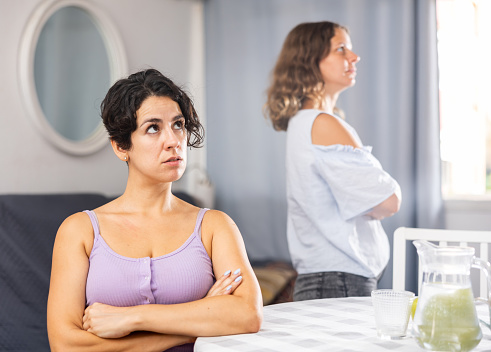 Stressed young LGBTQ female couple feeling offended after quarrel at home