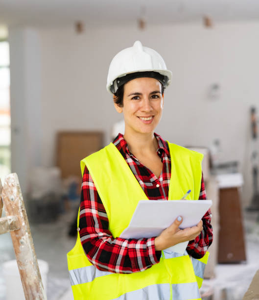 istock Woman engineer in construction vest smiling and checking documents during repair works 1487593861