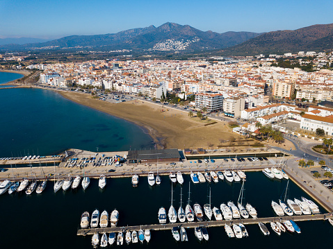 Aerial view of Mediterranean seascape of Roses town with yachts moored in harbor, Costa Brava, Spain