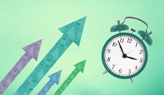 Alarm clock with different colors arrows showing growth on blue background. Business concept