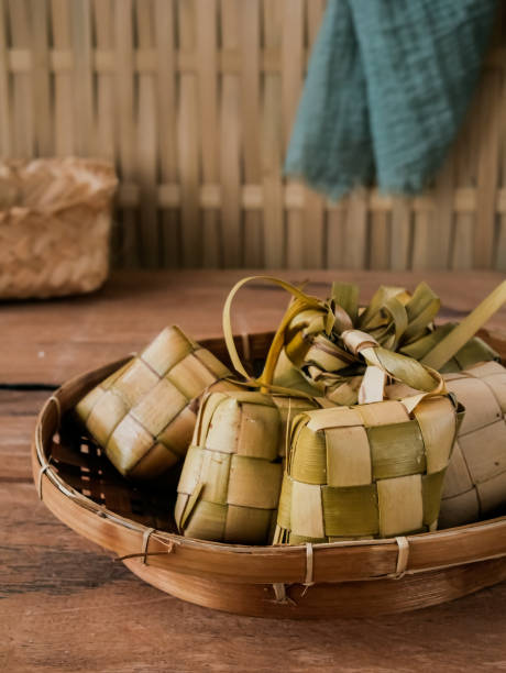 ketupat, prato especial servido no eid al fitr ou eid al adha ou lebaran. tripa de arroz natural feita de folhas de coco jovens, recheada com arroz e cozido.geralmente servida com opor ayam ou sayur ketupat - eid il fitr - fotografias e filmes do acervo