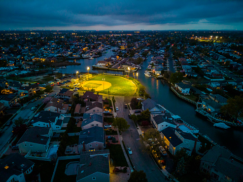 Illuminated public community baseball stadium in Oceanside, Long Island on sunset dark skyline, twilight. Aerial view