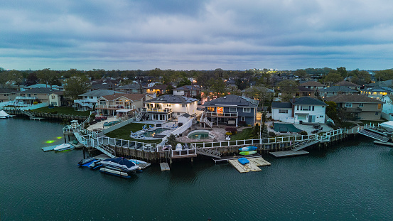 Nassau County, New York, Queens, Oceanside. Panoramic view of Atlantic waterfront of small town with boats on piers against cloudy sky