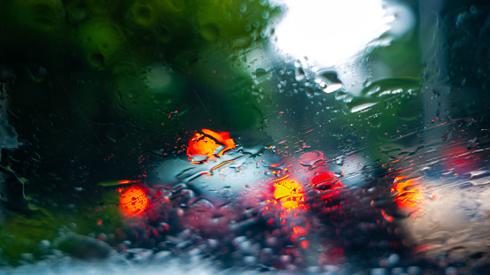 Defocused Traffic and raindrops on the windscreen of a car driving along the street at afternoon in Jakarta, Indonesia.