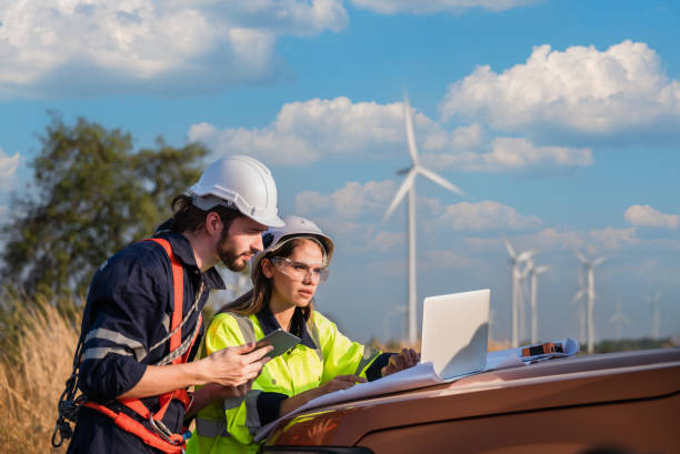 istock Two professional maintenance engineers in safety workwear using laptop and tablet checklist wind turbine on windmill construction farms. 1487628629