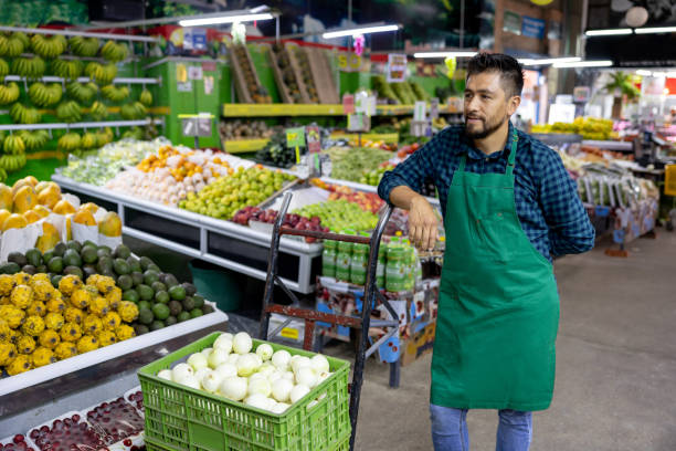 istock Man working at a greengrocer's shop stocking the shelves 1487628685