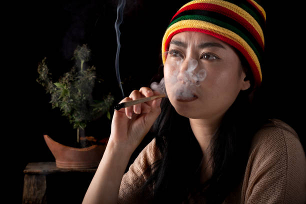 schöne asiatische frauen, die zigaretten rauchen, am hintergrund eines cannabisbaums - bob marley stock-fotos und bilder