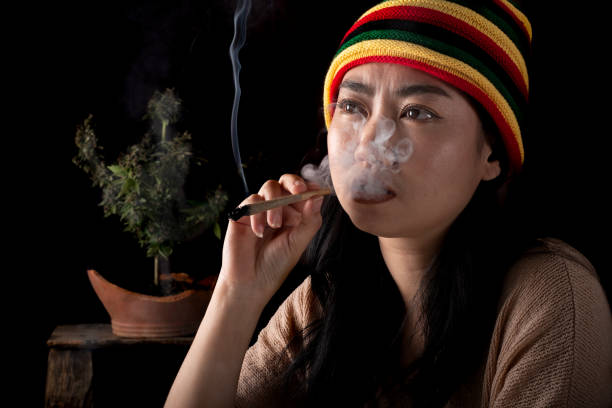 hermosas mujeres asiáticas fumando cigarrillos en el fondo del árbol de cannabis - bob marley fotografías e imágenes de stock