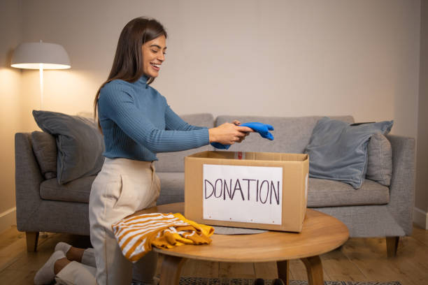 istock Young woman sorting clothing and packing donation box 1487639407