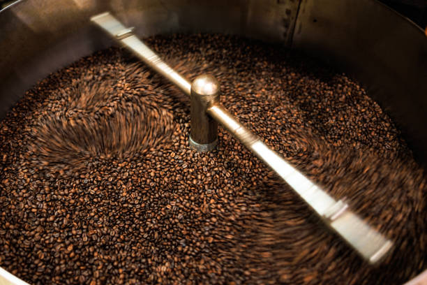 istock fresh coffee beans roasted spinning cover professional machine close up to soft focus  slow shutter speed because want to make motion blur of coffee beans detail concept, at factory chiang rai Thailand, 1487644090