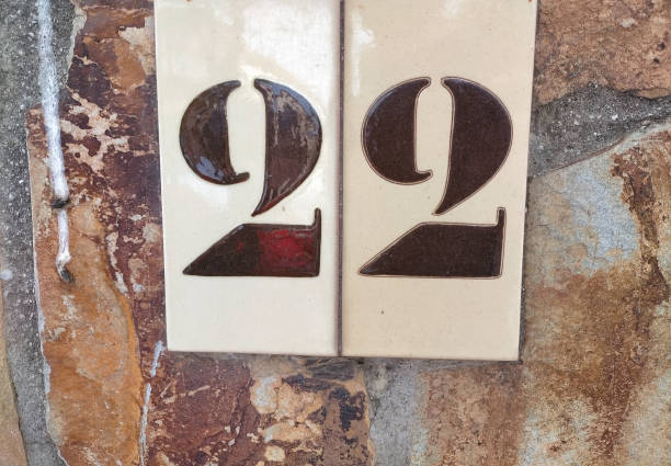 twenty-two, 22 in number on a brownish-white ceramic tile set atop a stone wall