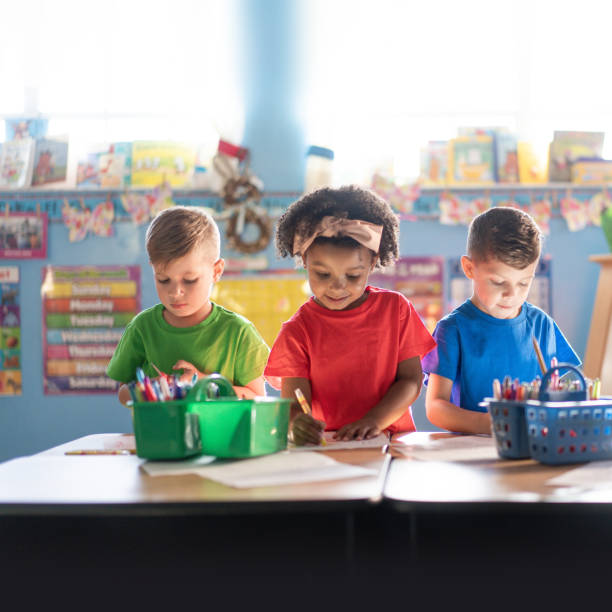 drei kinder im vorschulalter, die aktiv in einer fürsorglichen kindertagesstätte lernen und wachsen - reading and writing classroom alphabet learning stock-fotos und bilder