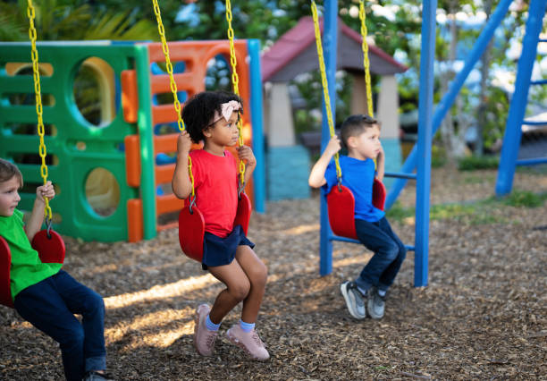 Three preschool kids are enjoying swinging together