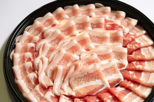 Several rows of sliced smoked low sodium bacon isolated on a white background.
