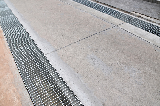 metal grate covers drain sewer parallel to both sides of concrete road, urban public utility construction industry