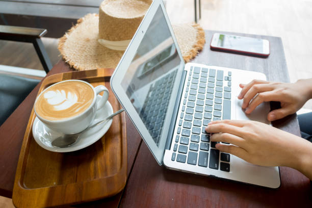 istock Women's hands typing on computer with coffee and smart phone 1487664347