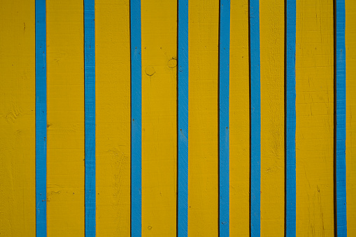 Vertical background wooden planks with cracked blue yellow paint