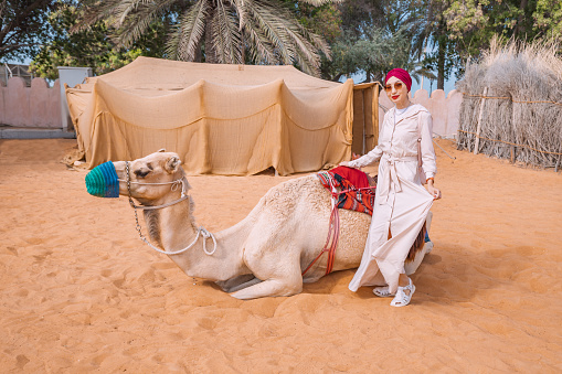 Embark on a cross-cultural journey with this Indian woman, as she rides a majestic camel through the winding paths of an Arabic heritage village.