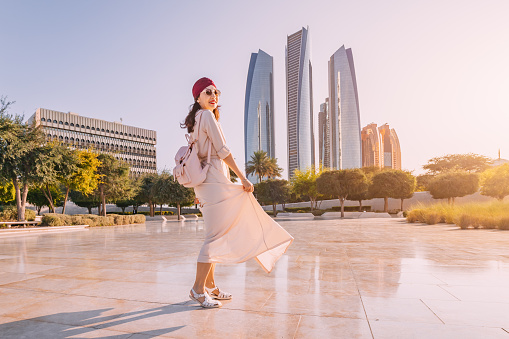 Experience the fusion of modernity and tradition as an Indian woman walks against the backdrop of Abu Dhabi's iconic skyscrapers.