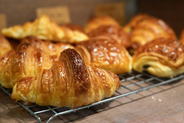 istock Freshly baked pastry and croissants in a bakery on a cooling rack. 1487675603
