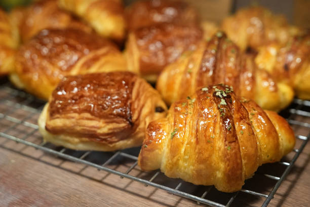 istock Freshly baked pastry and croissants in a bakery on a cooling rack. 1487675707