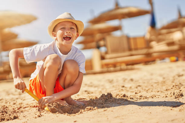 istock Image of a young boy playing with sand on the beach 1487677737